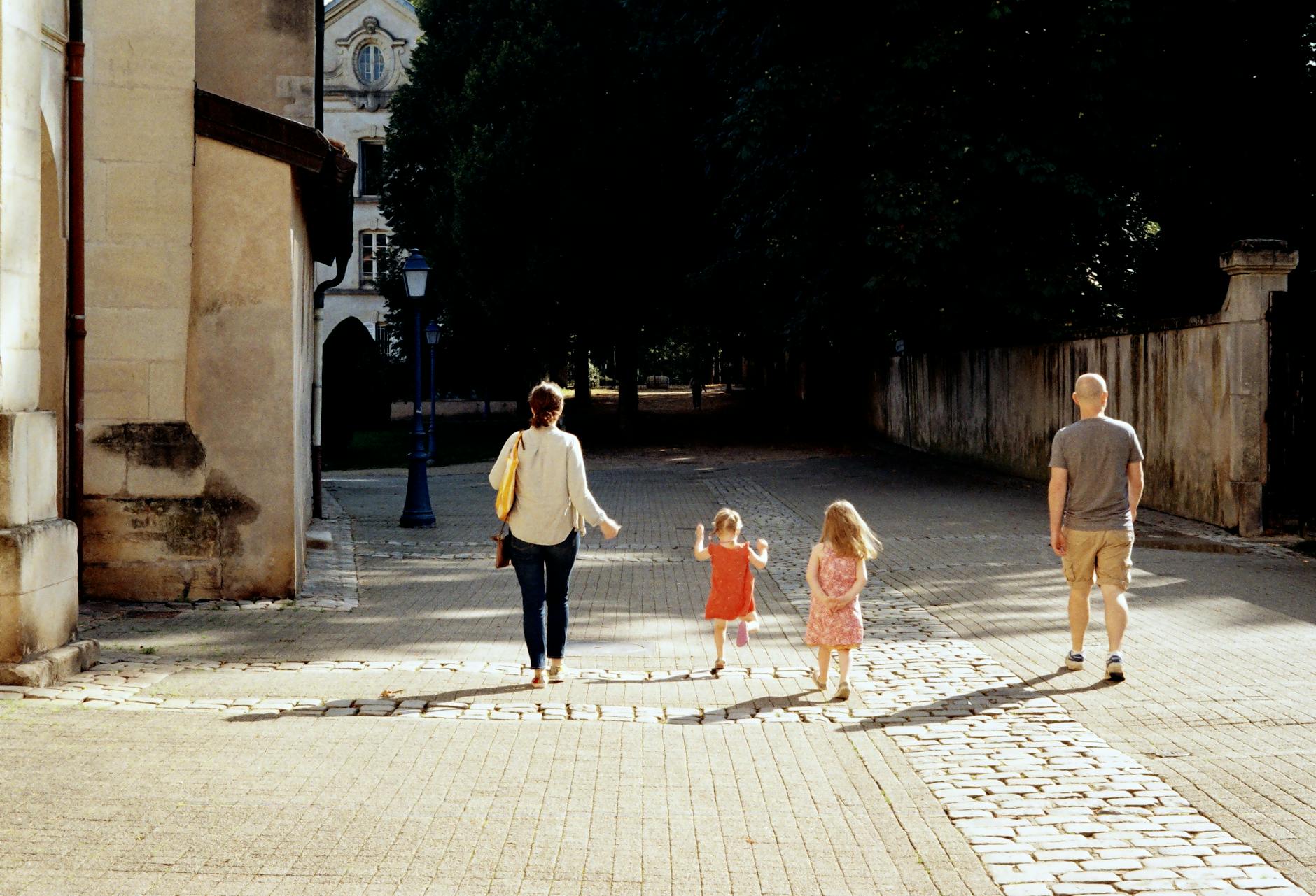 Rodzina z trójką dzieci spaceruje słoneczną uliczką w europejskim mieście